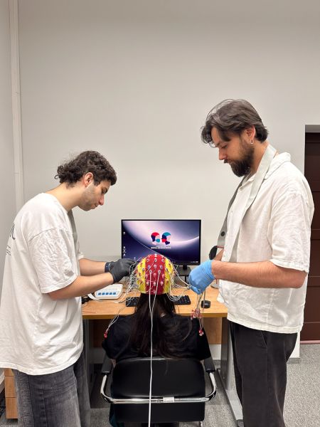 photograph: two persons readying an electroencephalograph for an experimant