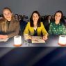 zdjęcie: trzy osoby stanowiące jury konkursu siedzą za stołem; za nimi, w tle, grupa kilkudziesięciu osób