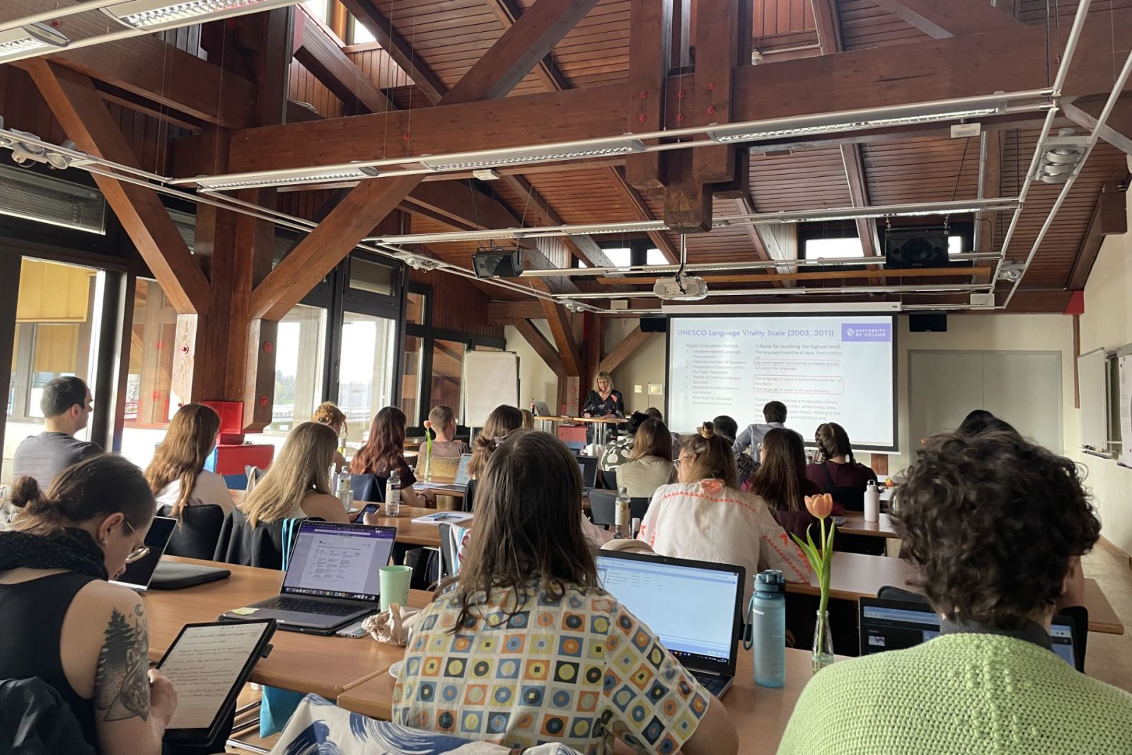 a group of people sitting in a large, well-lit classroom